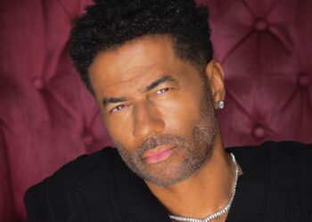 A photo of Eric Benét sitting on a burgundy velvet chair