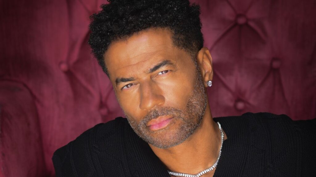 A photo of Eric Benét sitting on a burgundy velvet chair