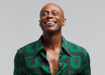 A photo of R&B singer Kem smiling, wearing a green shirt