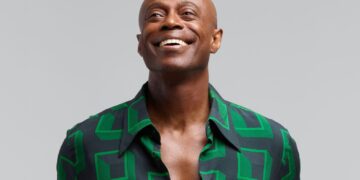 A photo of R&B singer Kem smiling, wearing a green shirt